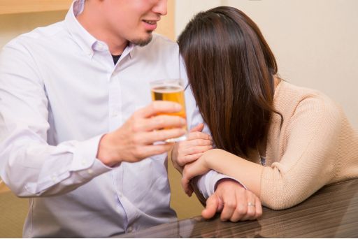 酔い潰れて男性に寄りかかるロングヘアの女性