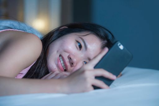 ベッドの中でスマホを触る女性