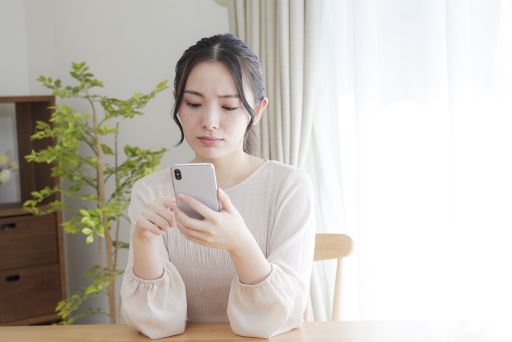 テーブルでスマホを眺める若い女性