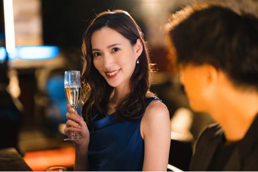 ワイングラスを持って男性の方を見る青いドレスの女性
