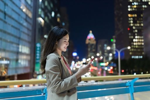 夜の屋外でスマホを触る若い女性