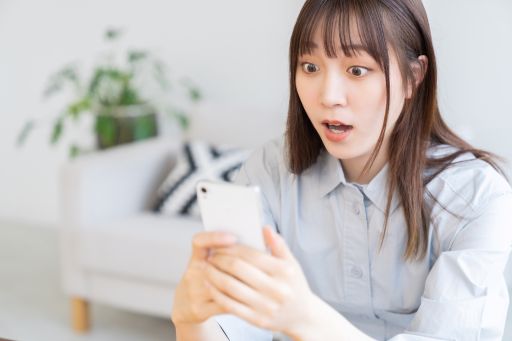 携帯を見て驚く女性