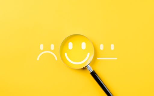 黄色の背景の前にある3つの顔と虫眼鏡