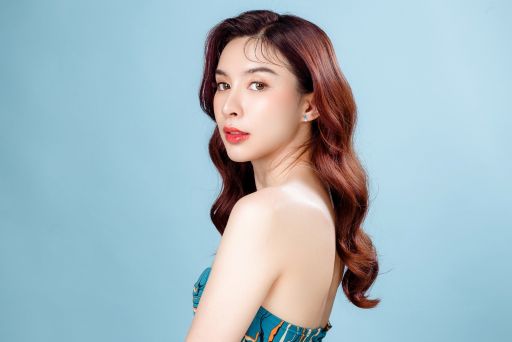 水色の背景の前でこちらを見る女性