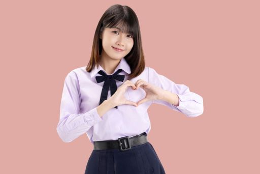 胸あたりでハートマークをつくる女性