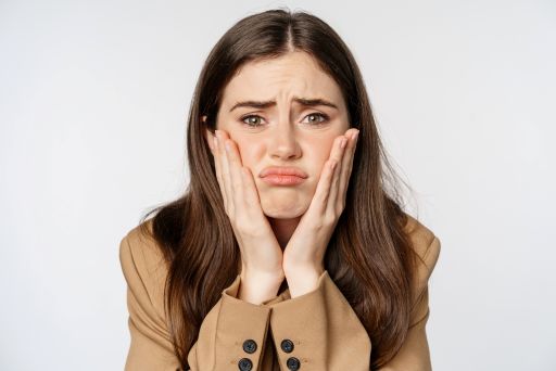 両頬に手をあててなにかに悩んでいる女性