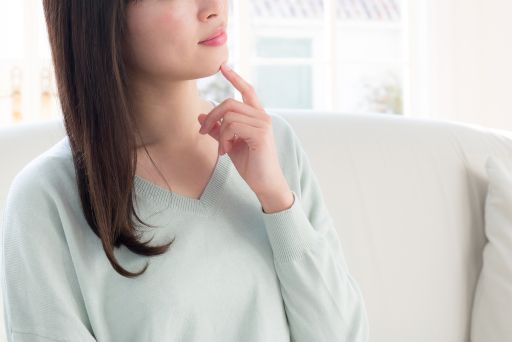 指を顎に当てて悩む女性
