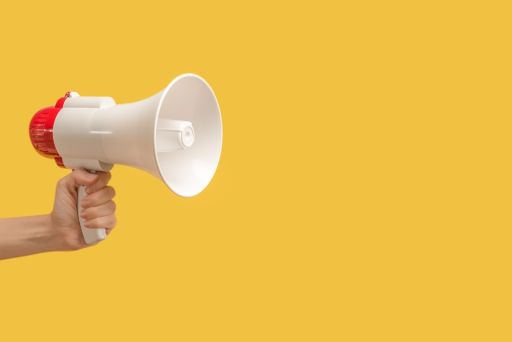 黄色の背景の前でメガホンを持つ女性