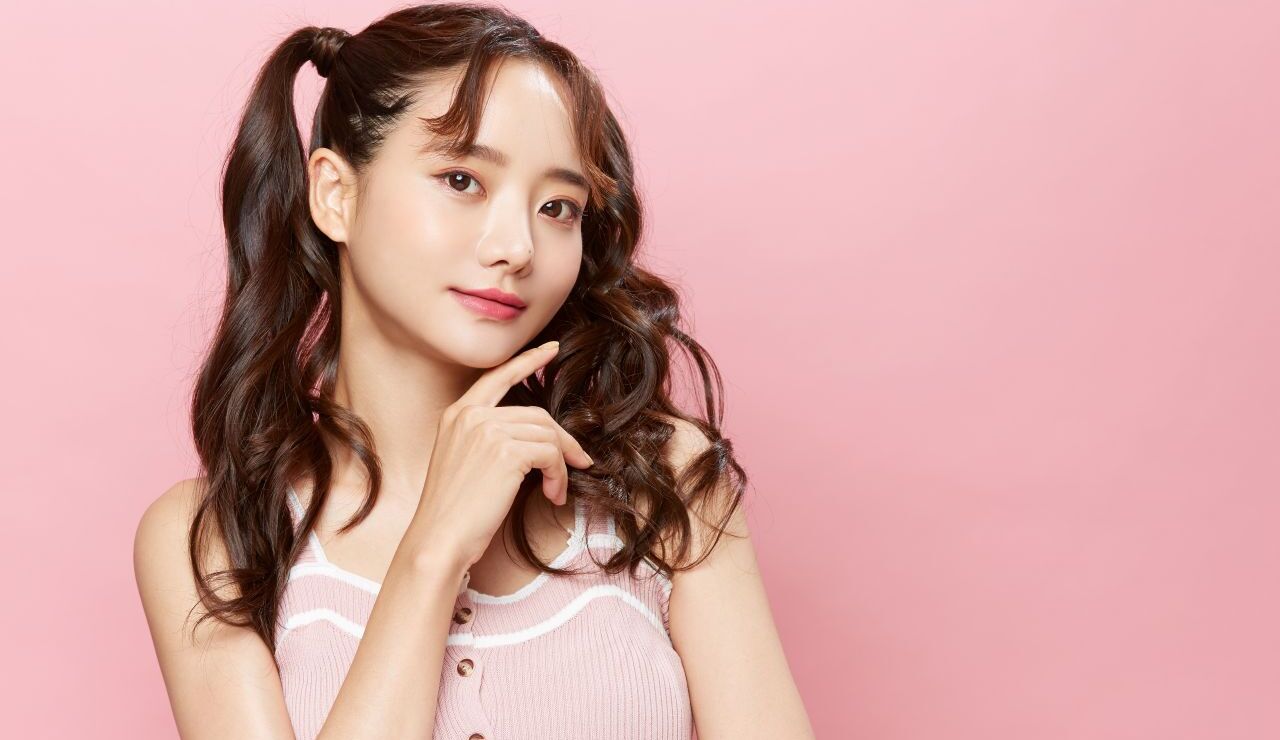 ピンクの背景の前でポーズを決めるツインテールの女性