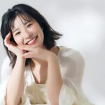 白い服を着て腕に頭を乗せて微笑む若い女性