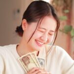 一万円札2枚と千円札1枚を胸に当てて笑顔の女性