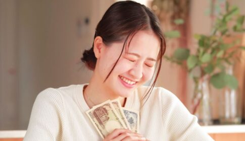 一万円札2枚と千円札1枚を胸に当てて笑顔の女性