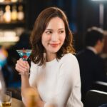 カクテルを飲みながら男性の方を向く若い女性