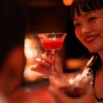 カクテルグラスを顔の横に持ちげる若い女性
