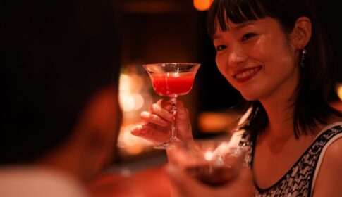 カクテルグラスを顔の横に持ちげる若い女性