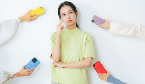 頭を抱えている女性とスマホを持った人の4本の手