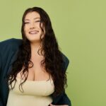 緑の背景の前でポーズをするぽっちゃりの女性