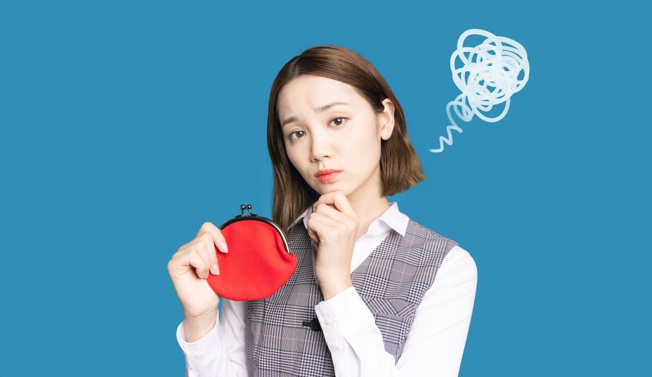 赤いお財布を持ちながら悩む女性
