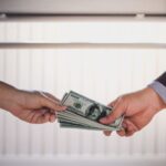 机の下でお金を受け渡しする男女の手